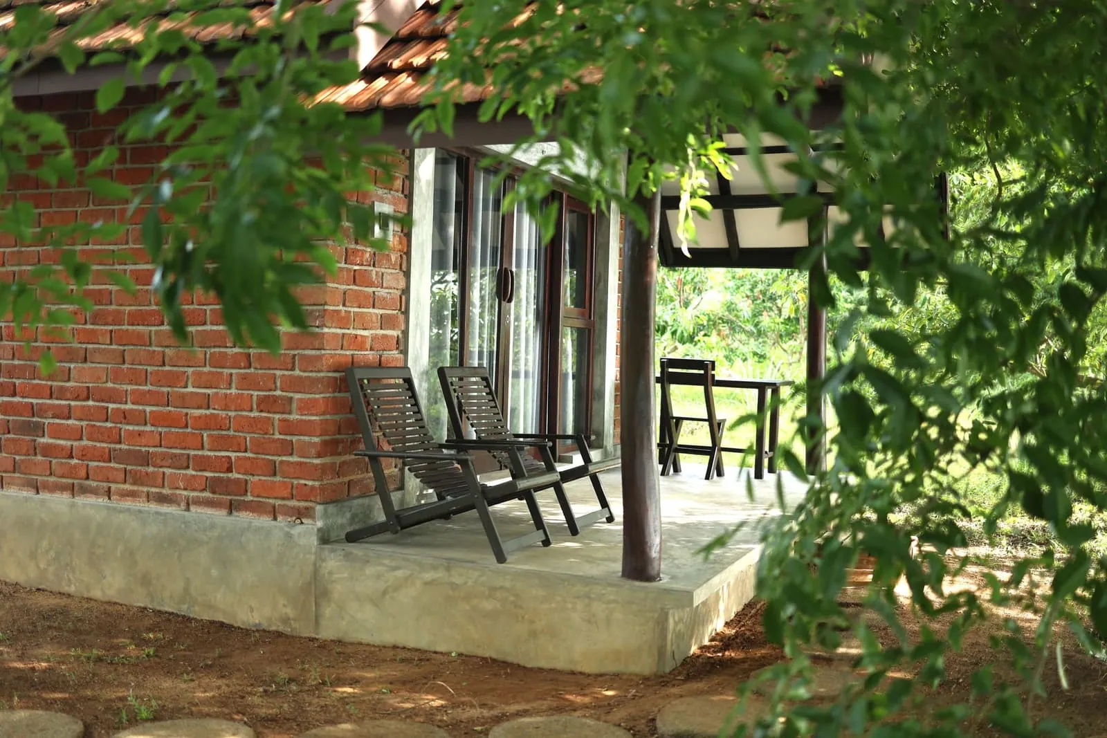 Brick cottage veranda with lounge chairs under trees