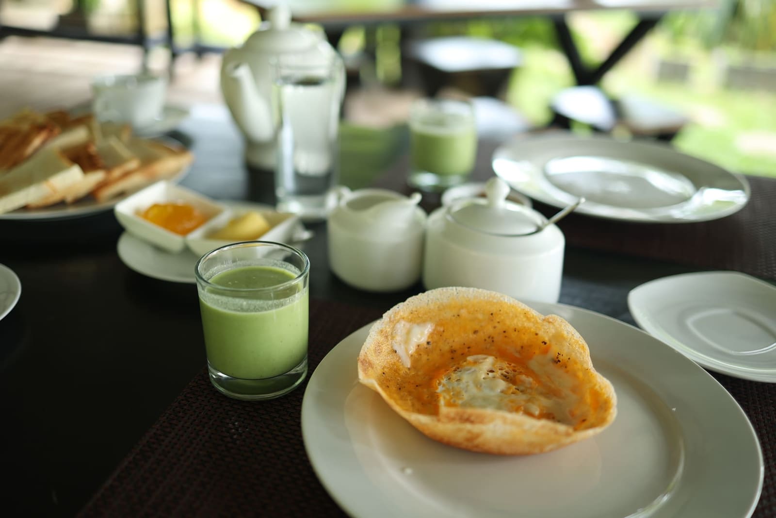 Fresh green juice with a Sri Lankan hopper, garden behind